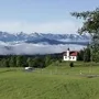 Kapelle auf Hügel vor Wolken und Bergen im Frühling.