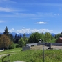Landschaft mit Wiesen, Bäumen und Bergen im Hintergrund bei klarem Himmel.