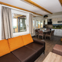 Wohnbereich mit Sofa, Tisch, Küche und Treppe in modernem Design.