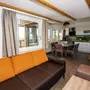 Wohnbereich mit Sofa, Tisch, Küche und Treppe in modernem Design.