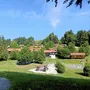 Ferienhäuser auf einem Hügel, umgeben von Bäumen und einer Wiese.