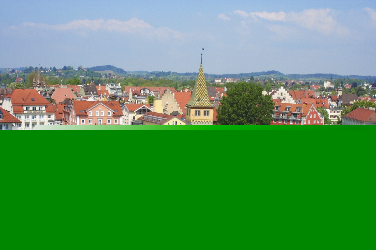 Blick auf Lindau am Bodensee mit Hafen, Booten und historischen Gebäuden unter leicht bewölktem Himmel.