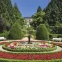 Gepflegter Park mit rundem Blumenbeet und Palmen in sonniger Umgebung.
