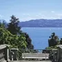 Blick von Treppe auf Bodensee mit Segelbooten und Bergen im Hintergrund.