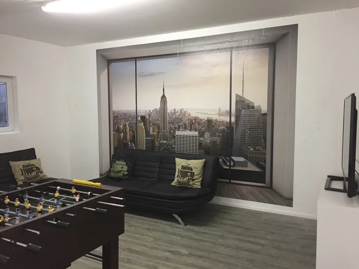 Jugendraum mit Sofa, Tischkicker und Fototapete von New York Skyline.