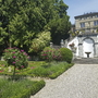 Gartenanlage mit Blumen, Treppe und historischem Gebäude im Hintergrund.