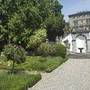 Gartenanlage mit Blumen, Treppe und historischem Gebäude im Hintergrund.