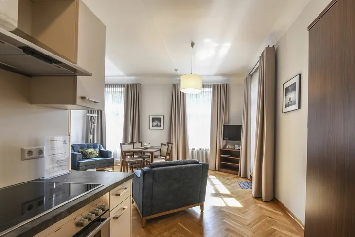 Wohnzimmer mit Küche, Esstisch, Sofa und TV in einer hellen Wohnung.