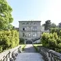 Historische Villa mit Garten und Steinweg in Lindau, umgeben von Bäumen.