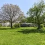 Grüne Wiese mit grünen und blühenden Bäumen sowie den Appartementhäusern an der Obstwiese, der Ferienanlage Lindau, im Hintergrund.