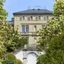 Historische Villa mit Gartenansicht, umgeben von blühenden Bäumen.