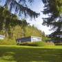 Bungalows der Ferienanlage Prüm auf einer grünen Wiese, umgeben von Bäumen.