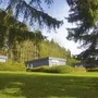 Bungalows der Ferienanlage Prüm auf einer grünen Wiese, umgeben von Bäumen.