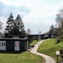 Pfad führt zu modernen Ferienhäusern der Ferienanlage Prüm in grüner, bewaldeter Landschaft.