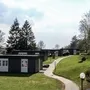 Pfad führt zu modernen Ferienhäusern der Ferienanlage Prüm in grüner, bewaldeter Landschaft.