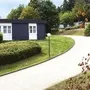 Kleine Bungalows der Ferienanlage Prüm an einem gewundenen Weg in einer grünen, bewaldeten Umgebung.