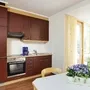 Dunkelrote Küche mit Esstisch und Blumenarrangement in der Ferienanlage Prüm.