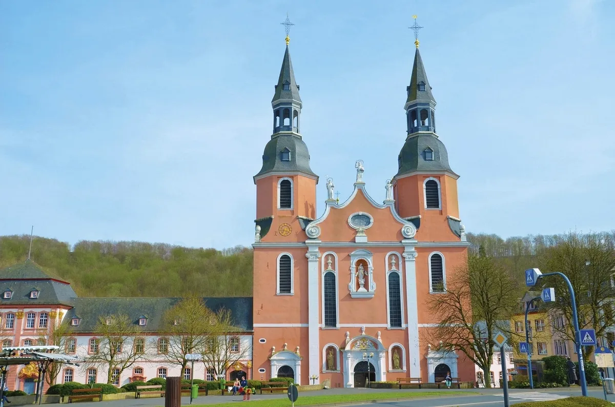 Basilika in Prüm mit zwei Türmen und barocker Fassade bei blauem Himmel.