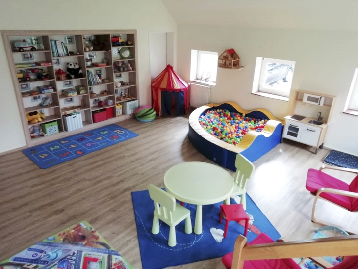Spielzimmer mit Bällebad, Tisch, Stühlen und Regalen voller Spielsachen in Ferienanlage Harlesiel.