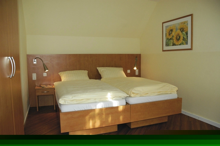 Schlafzimmer mit Doppelbett, Nachttisch und Sonnenblumenbild an der Wand in Ferienanlage Harlesiel.