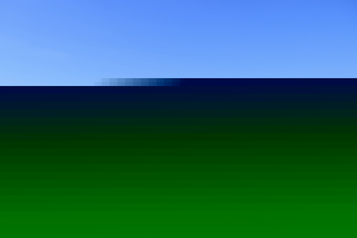 Hölzerne Aussichtsplattform mit Blick auf bewachsene Dünenlandschaft und Meer unter blauem Himmel.