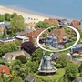Luftaufnahme der Ferienanlage Wyk auf Föhr, umgeben von Häusern und Bäumen sowie einer Windmühle, in der Nähe des Strandes.