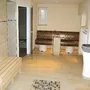 Innenraum einer Sauna mit Holzbänken und Fliesenwänden.