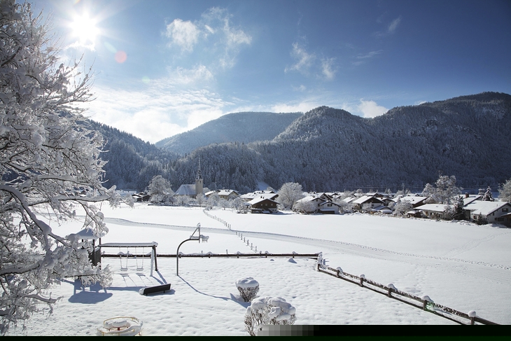 Winterlandschaft in Oberwössen mit schneebedeckten Häusern und Bergen bei Sonnenschein