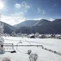 Winterlandschaft in Oberwössen mit schneebedeckten Häusern und Bergen bei Sonnenschein