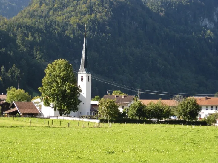 Kirche im Grünen vor bewaldeten Bergen im Ort Oberwössen.