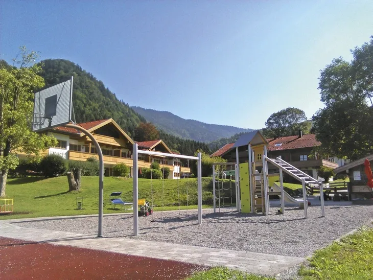 Spielplatz mit Klettergeräten und Rutsche vor Bergkulisse in Oberwössen.