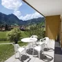 Terrasse mit weißen Stühlen und Tisch, Blick auf Berglandschaft und Dorf.