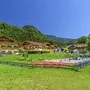 Außenansicht moderner Gebäude vor bewaldeten Bergen bei klarem Himmel.