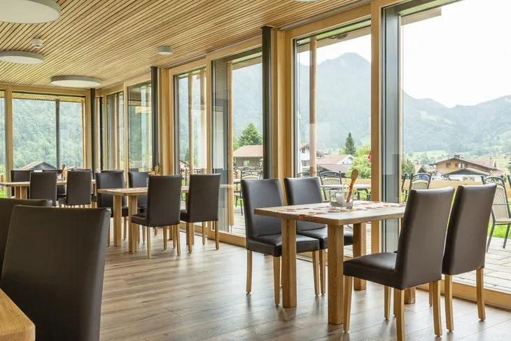 Moderne Restaurant-Innenansicht mit großen Fenstern und Bergblick.