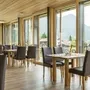 Moderne Restaurant-Innenansicht mit großen Fenstern und Bergblick.