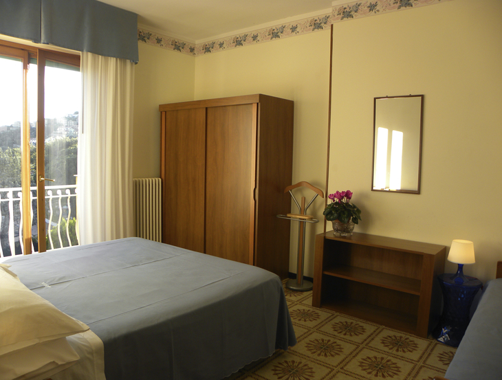Schlafzimmer mit Doppelbett, Kleiderschrank, Fenster und Nachttischlampe.