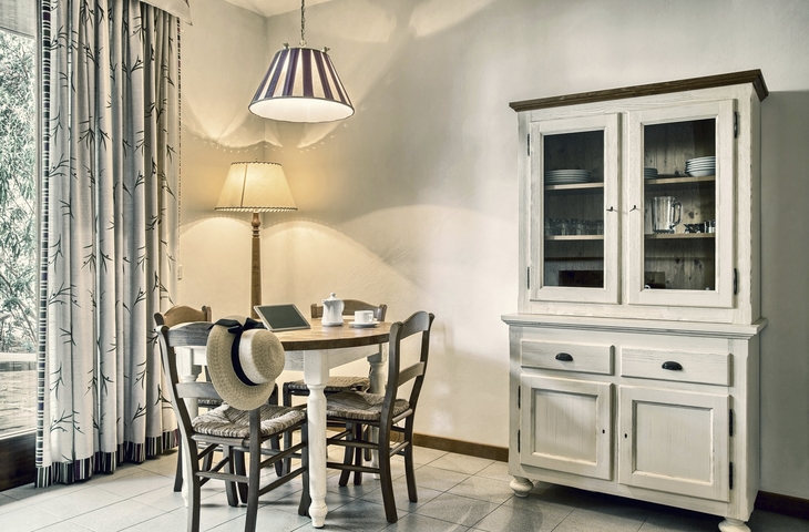 Essbereich mit Holztisch, vier Stühlen, Schrank und Lampe.