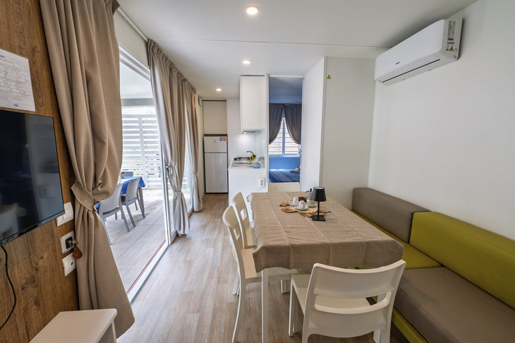 Innenansicht eines modernen Mobilheims mit Essbereich und Terrasse im Rosolina Mare Club.