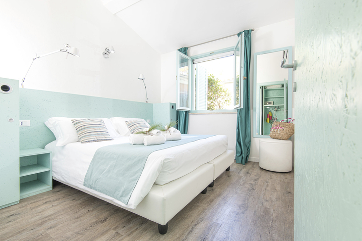 Helles Schlafzimmer mit Doppelbett und türkisfarbener Dekoration.