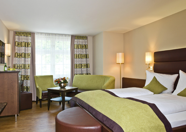 Doppelzimmer im Hotel König Passau mit Bett, Sitzecke und Fenster.