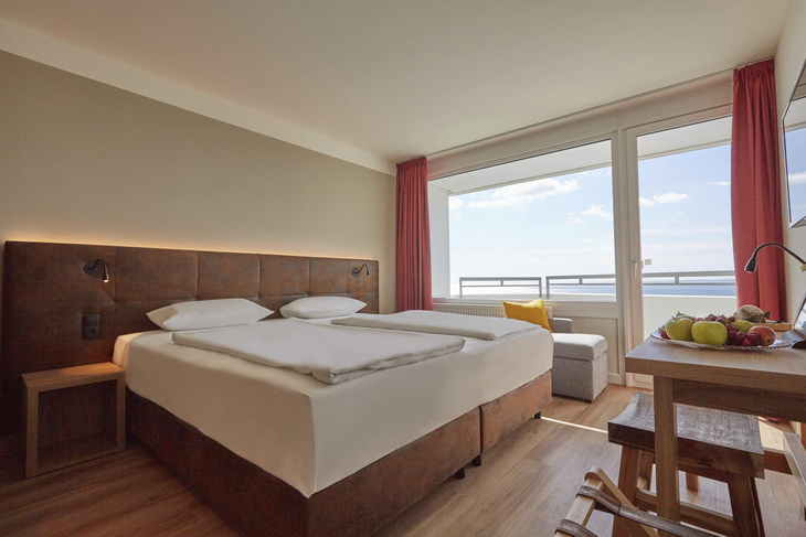 Komfortables Hotelzimmer mit Doppelbett, großem Fenster und Sitzbereich.