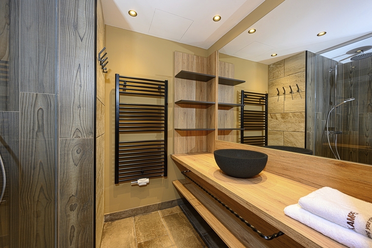 Modernes Badezimmer mit Holzregalen, Waschbecken und Handtüchern.