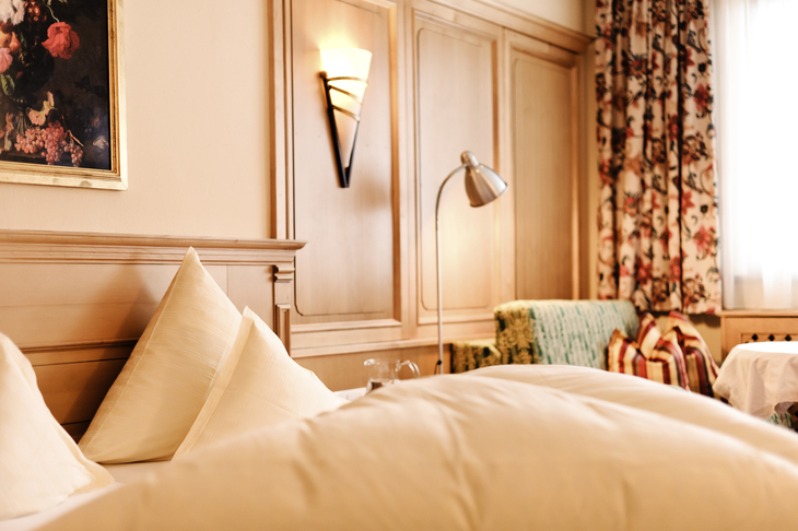 Doppelzimmer mit Bett, Leselampe und Wanddekoration.
