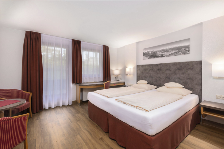 Standard-Doppelzimmer mit zwei Betten, Schreibtisch und roter Einrichtung.