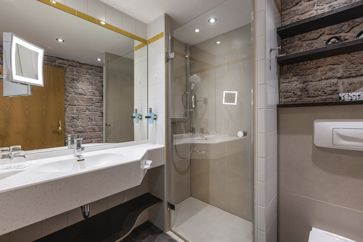 Modernes Badezimmer mit Dusche, Waschbecken und Spiegel im IFA Hotel Alpenrose.