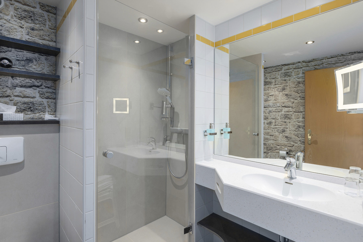 Modernes Badezimmer mit Glasdusche und Doppelwaschbecken in einem Hotelzimmer.