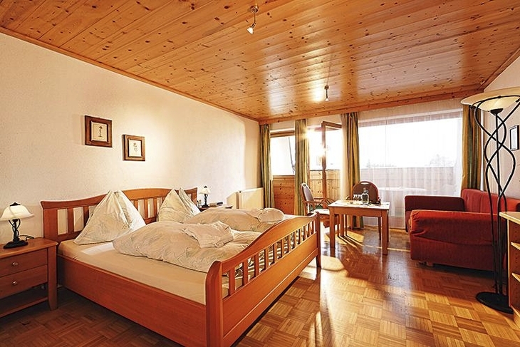 Ein gemütliches Hotelzimmer mit Holzmöbeln und Balkonansicht.