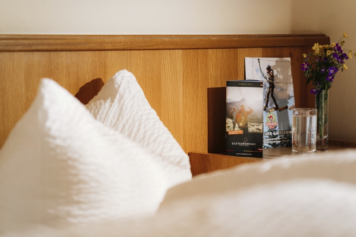 Hotelzimmer mit bequemen Kissen und Bücherregal im Hintergrund.