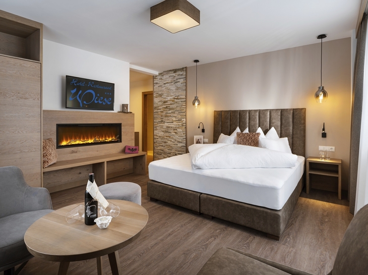 Hotelzimmer mit Doppelbett, Kamin und moderner Einrichtung.