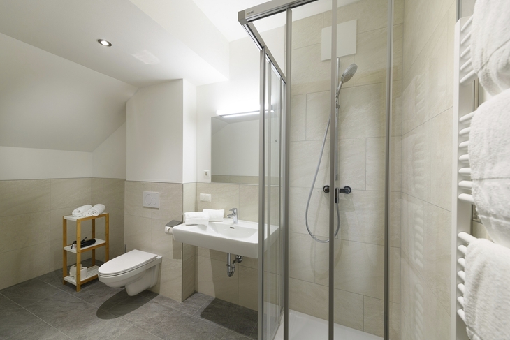 Moderner, helles Badezimmer mit Glasdusche und weißen Handtüchern.